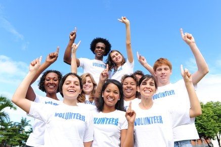portrait of a happy and diverse volunteer group hands raised